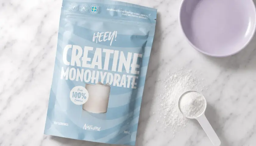 Påse med HEEY! Kreatin Monohydrat, perfekt för kreatin laddning. Pulver och skopa syns bredvid.