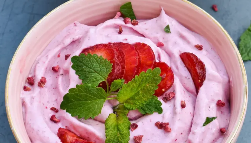 Keso glass med jordgubbar och mynta. En rosa, krämig dessert med färska jordgubbskivor och torkade bär.