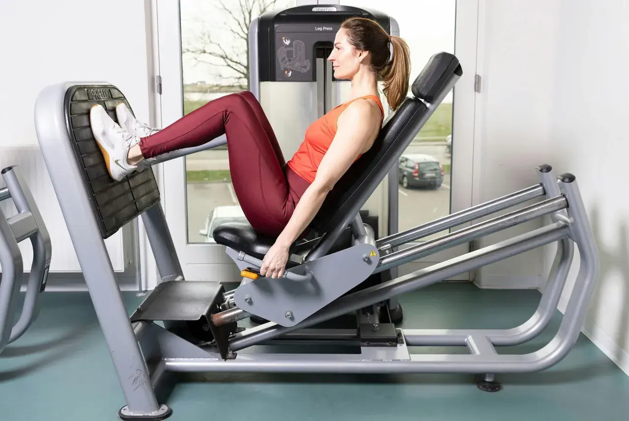 Kvinna tränar benpress i gymmet.