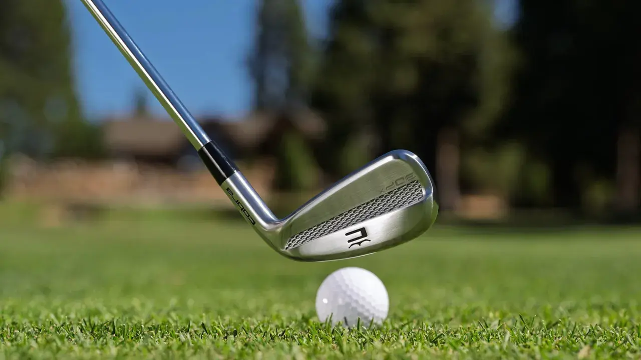En golfklubba av märket Cobra närmar sig en golfboll på en grön gräsmatta. Frågan om hur långa golfklubbor ska man ha är central för spelet.