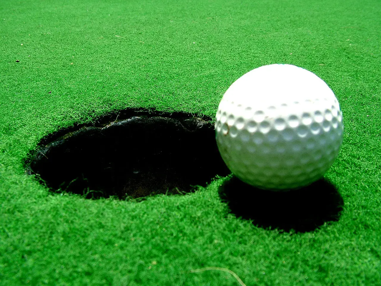 Vacker golfbana i Sverige med gröna fairways, bunkrar och vattenhinder. En flagga markerar ett golfhål med standard diameter.