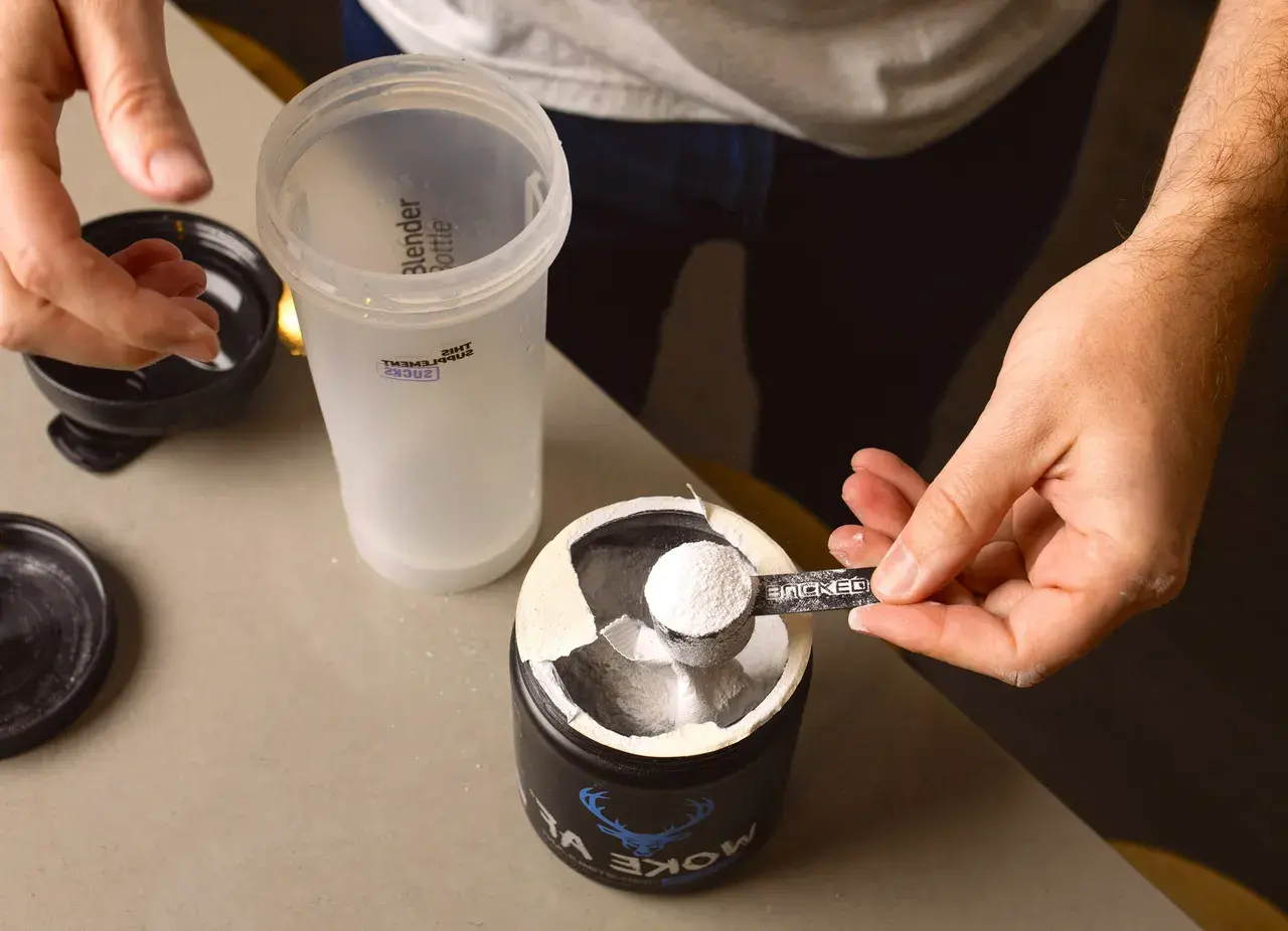 En hand skopar kreatinpulver från en burk till en shaker. Dags för en paus från kreatinuppehåll, eller kanske en ny start?