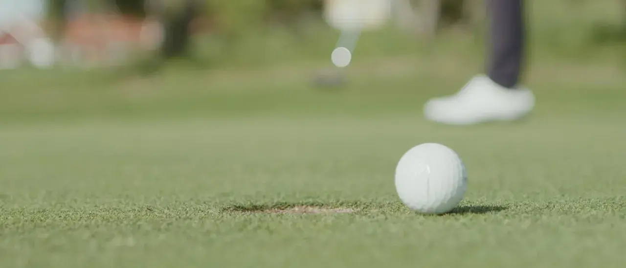 En golfspelare puttar bollen mot hålet under en handicapgrundande rond.