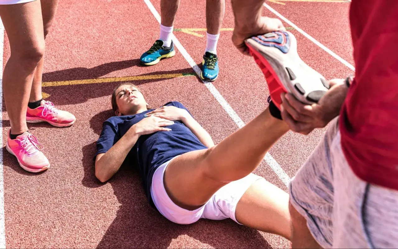 En löpare ligger på en bana medan en annan person hjälper till med stretching. Kanske en av zma biverkningar?