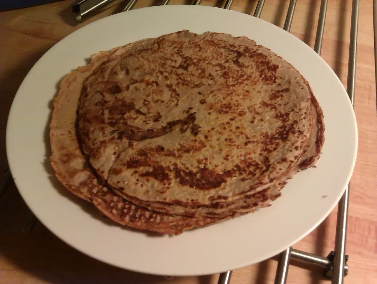 En hög med gyllenbruna proteinpannkakor på en vit tallrik. Perfekt för ett hälsosamt proteinpannkakor recept.