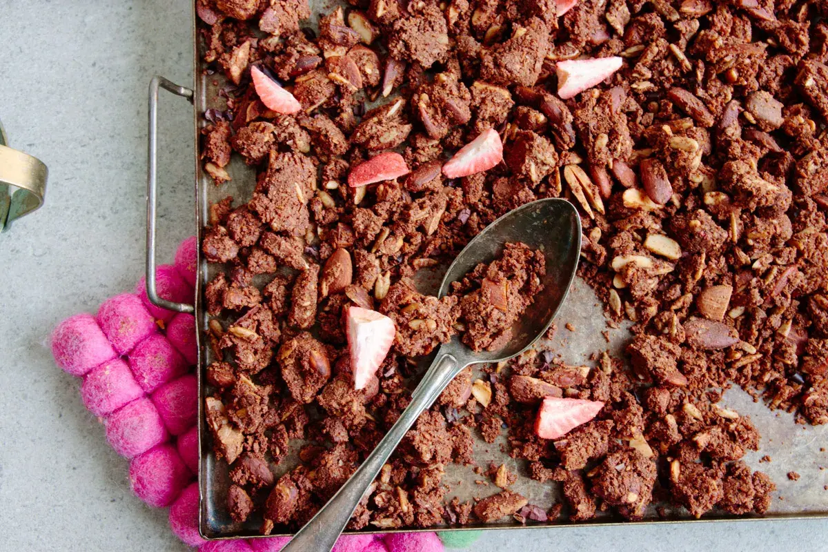 En sked tar en rejäl bit av hemgjord granola choklad med mandlar och jordgubbar.