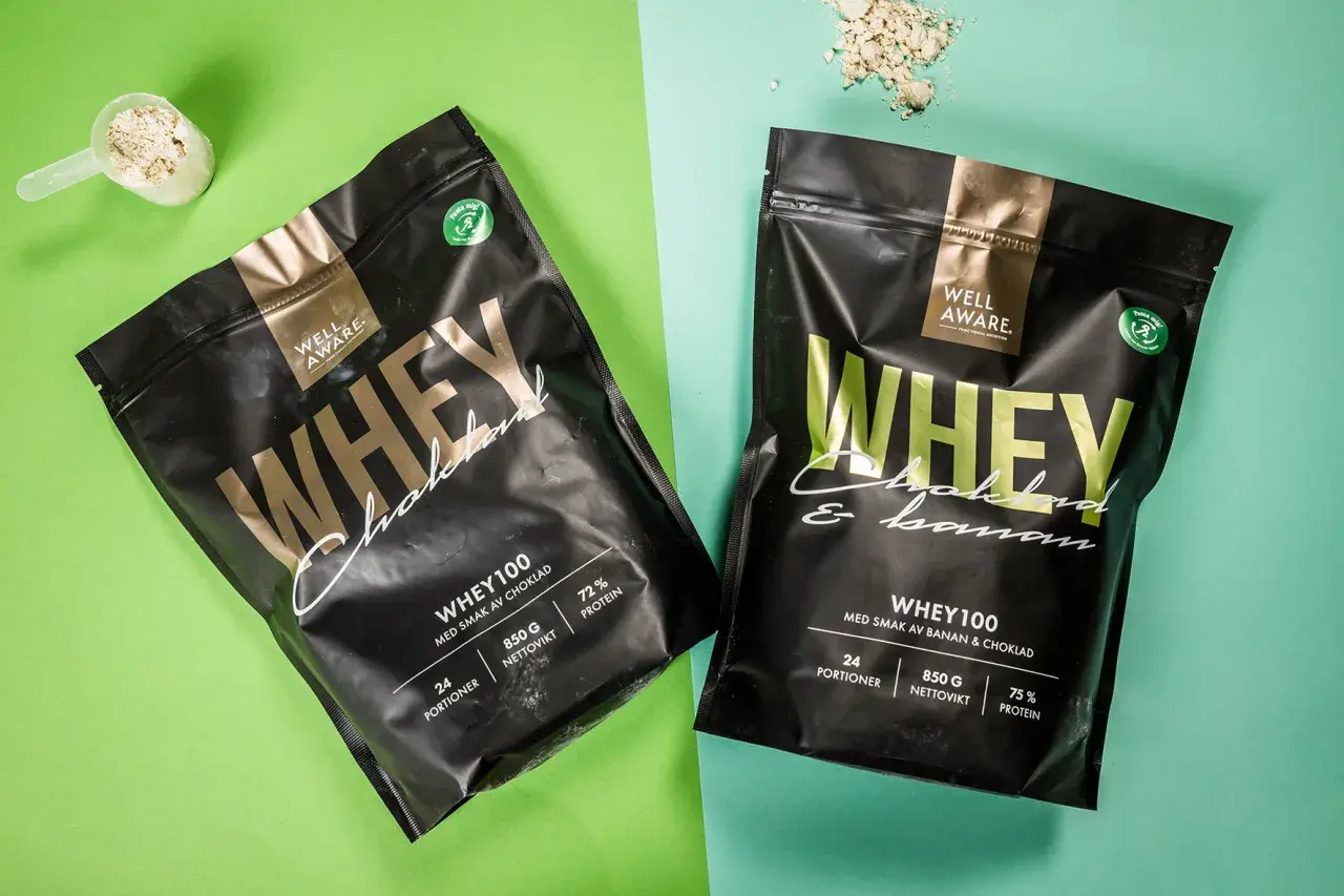 Två påsar Well Aware Whey100, en med chokladsmak och en med banan & choklad. Jämför whey 100 vs 80 för din träning.