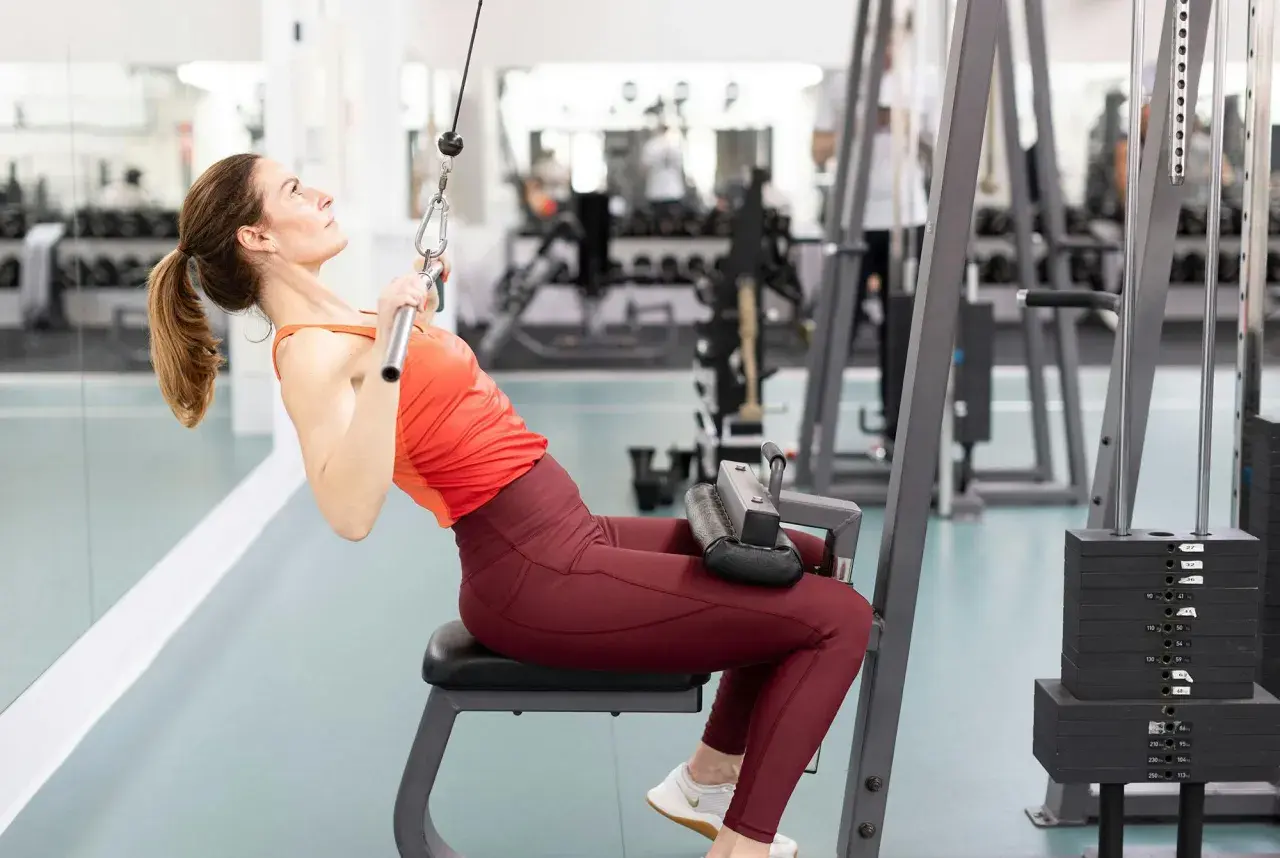 Kvinna tränar enarms latsdrag på gym.
