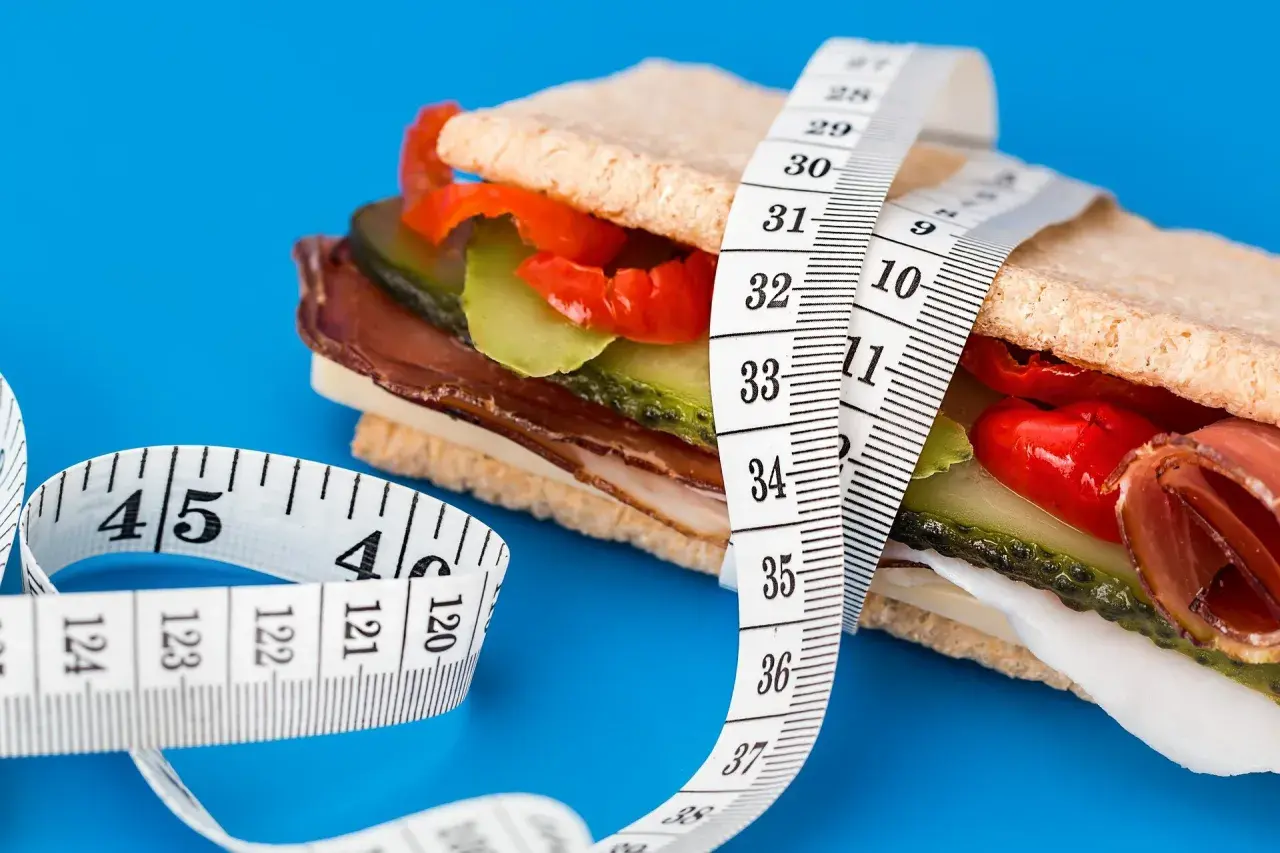 En mätsticka lindad runt en proteinrik smörgås, en visuell representation av att protein kan hjälpa till att gå upp i vikt.