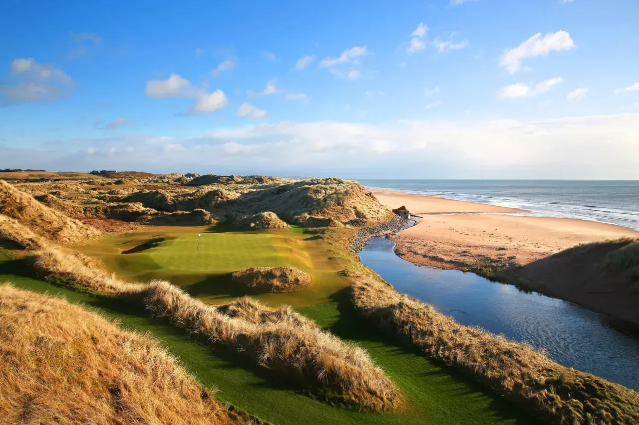En golfbana vid havet, med böljande sanddyner och en porlande bäck. En vy som påminner om golf historia.