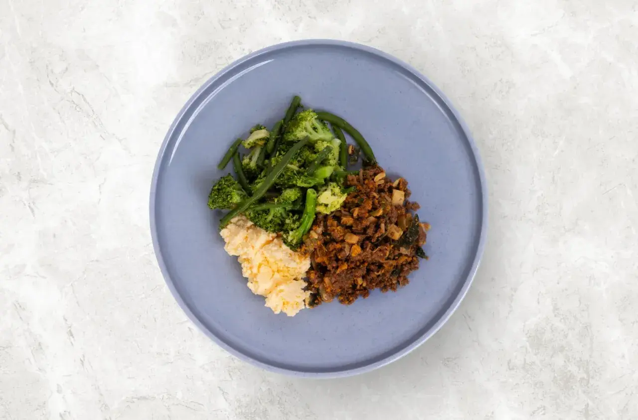 En tallrik med mat utan kolhydrater och socker: äggröra, broccoli med gröna bönor och köttfärs.