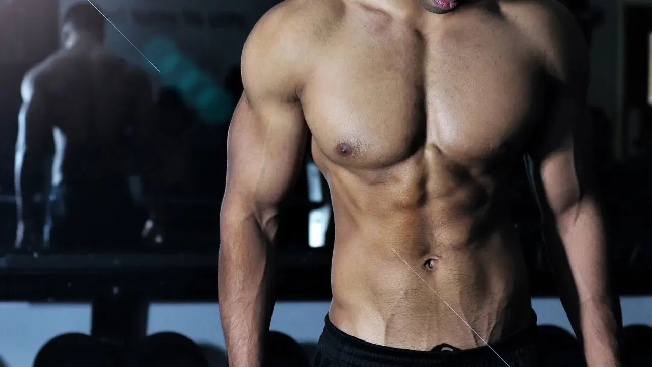 Muskulös man i gym, med fokus på magmuskler och armar. Bra inspiration för viktnedgång tips och träning.