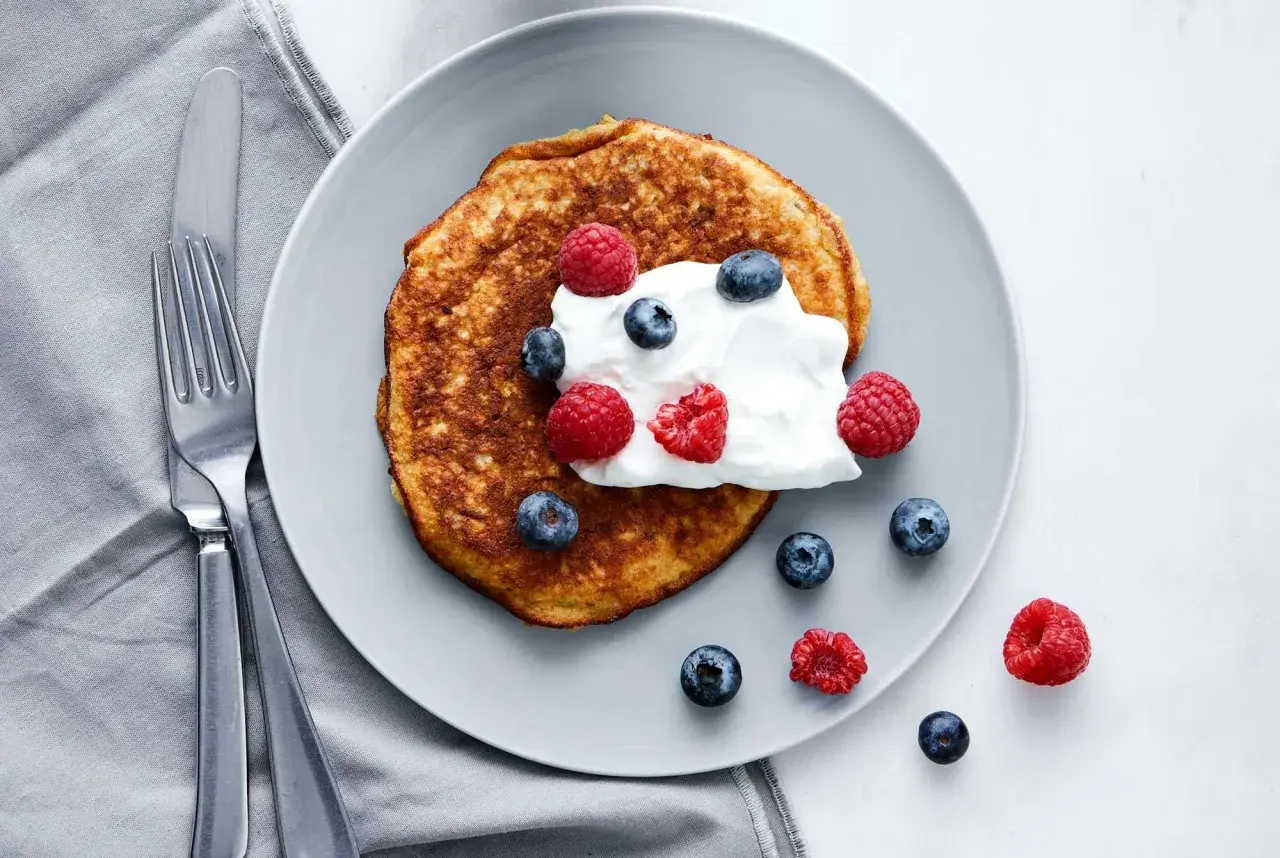 En gyllene pannkaka toppad med grädde och färska bär. En perfekt start på dagen med en nyttig frukost.