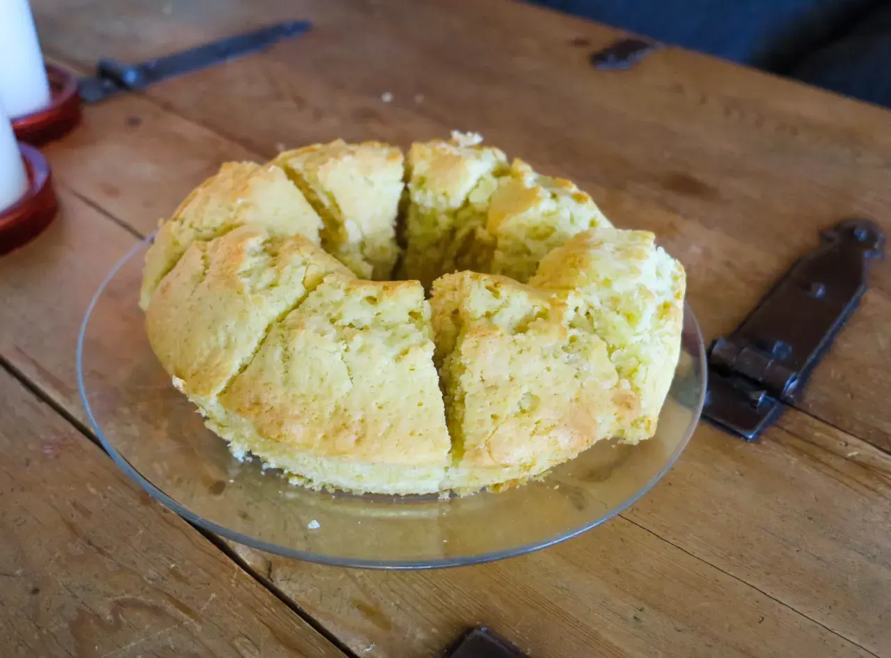 En saftig sockerkaka, uppskuren i bitar, ligger på ett fat på ett träbord.