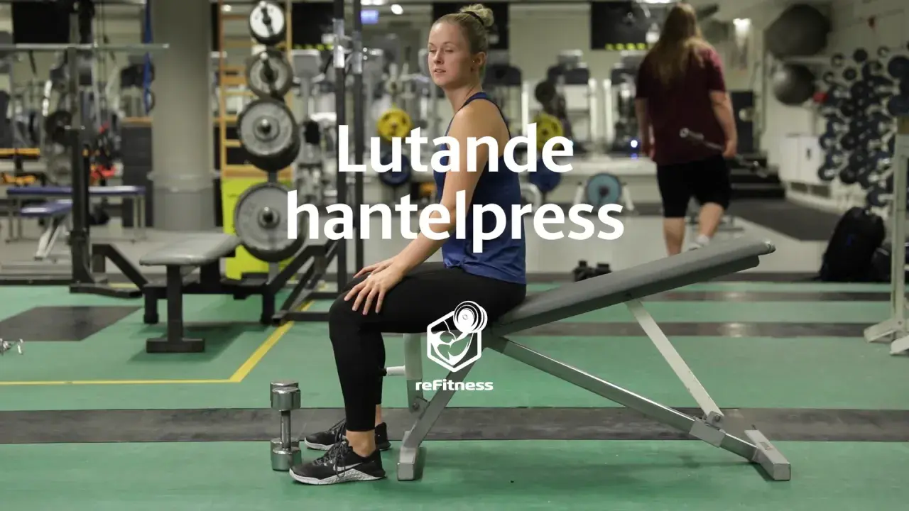 Kvinna förbereder sig för lutande hantelpress på gym. Hantlar ligger på golvet.