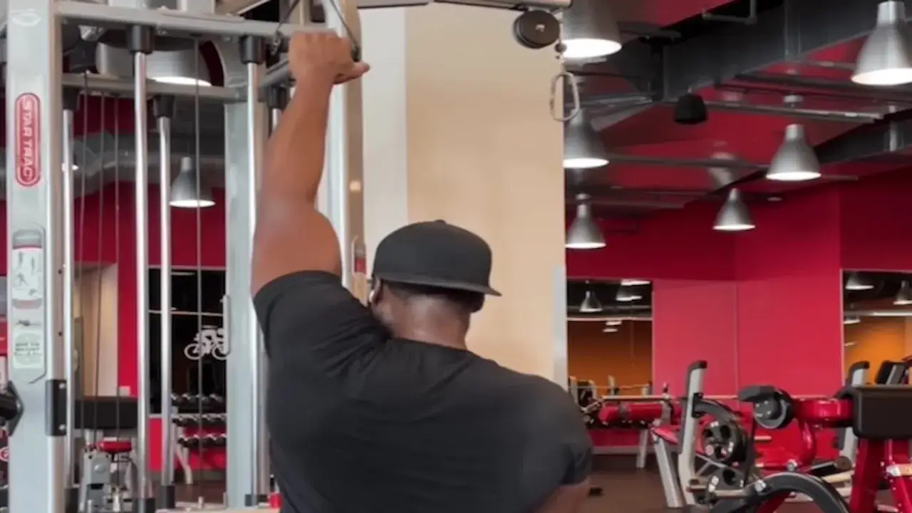 Man tränar enarms latsdrag på gymmet.