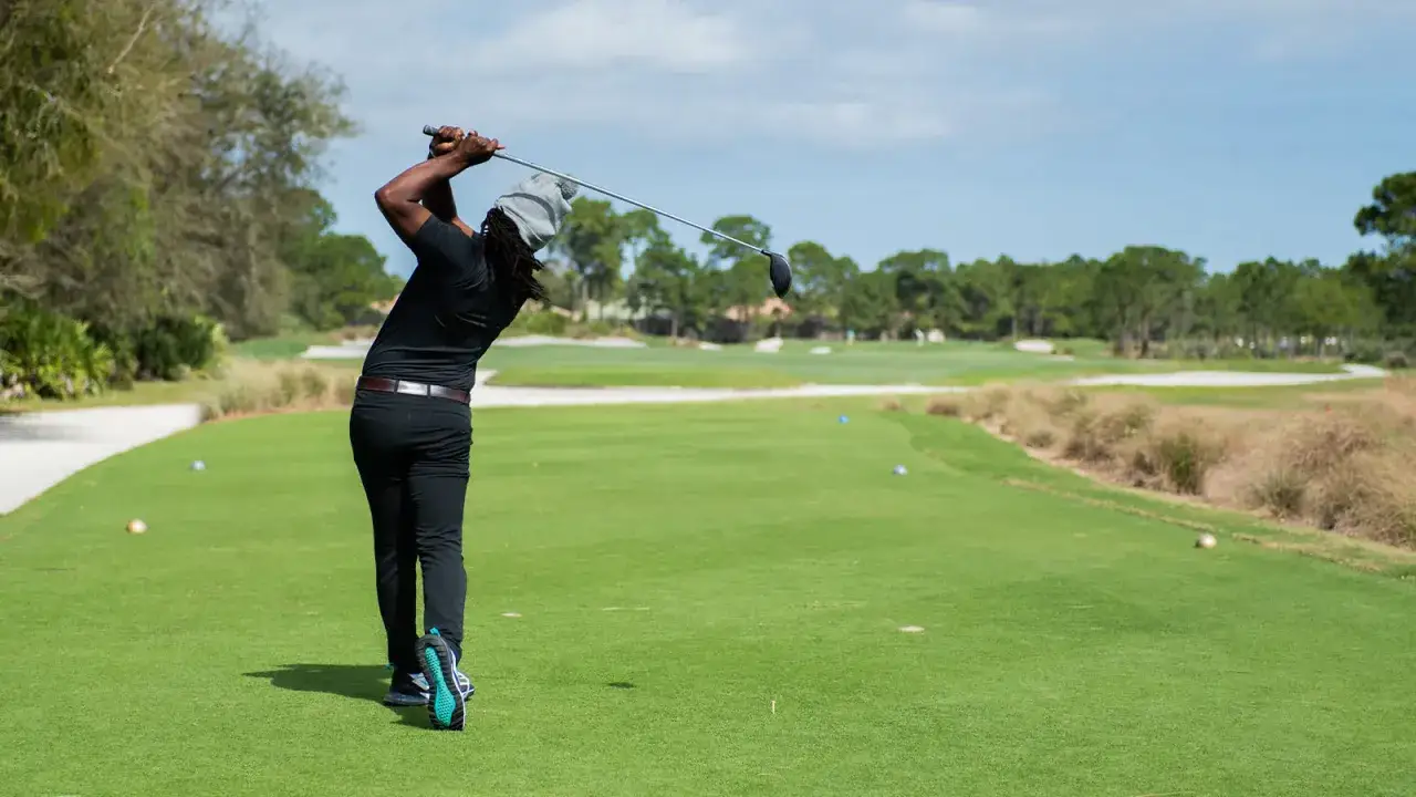 En golfare svingar klubban på en grön bana, redo för nästa slag i sin challenge tour.