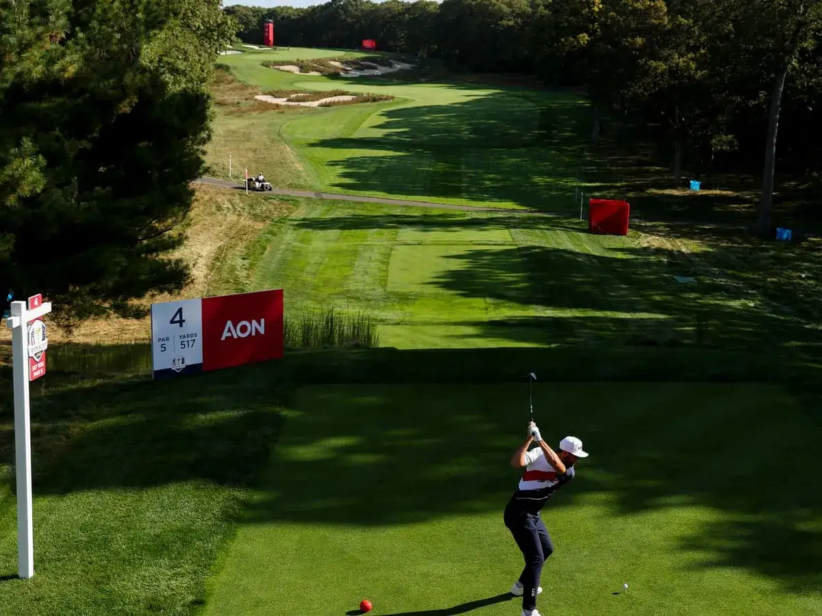 En golfare svingar sitt klubba på ett hål i golf, med en skylt som visar