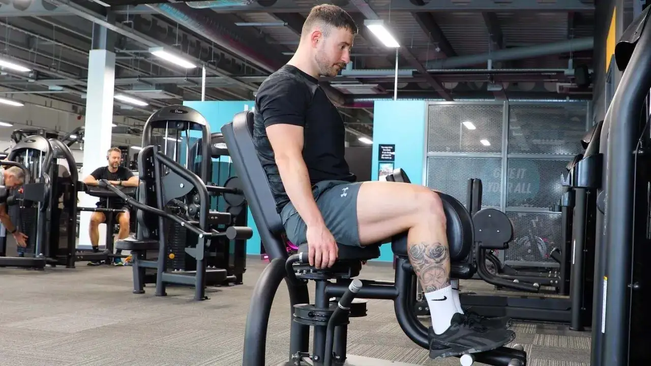 Man tränar insida lår på adductor maskin i ett modernt gym.