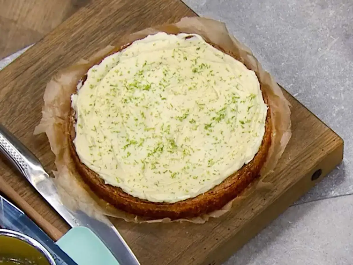 En saftig morotskaka med krämig frosting och rivet limeskal, redo att avnjutas.