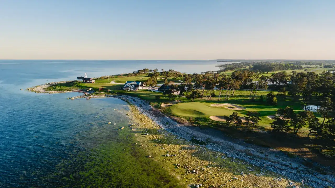 Vacker kustlinje med fina golfbanor i Sverige. En fyr och klubbhus vid det blå havet.