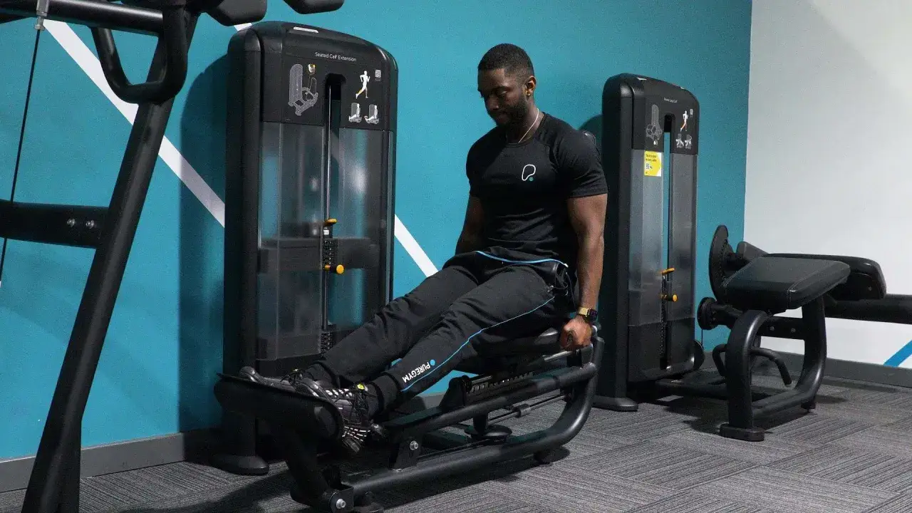 Man tränar sittande vadpress på ett gym.