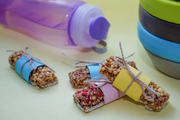 Energibars med nötter och frukt, perfekta för snabba kalorier. En lila vattenflaska och en stapel skålar i bakgrunden.