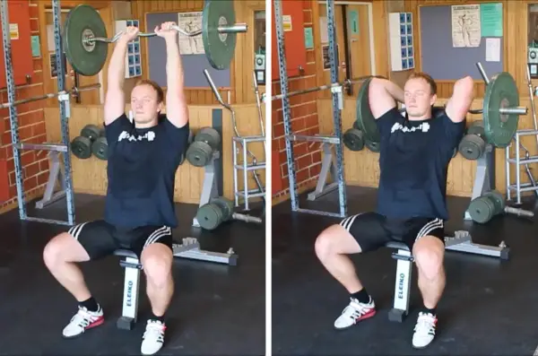 Man utför french press i gym. Han sitter på en bänk och håller en skivstång över huvudet.